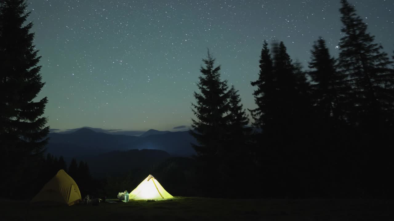 在星光闪烁的夜空下，登山者在明亮的篝火旁休息的时间间隔。积极的生活方式和户外生活理念视频素材