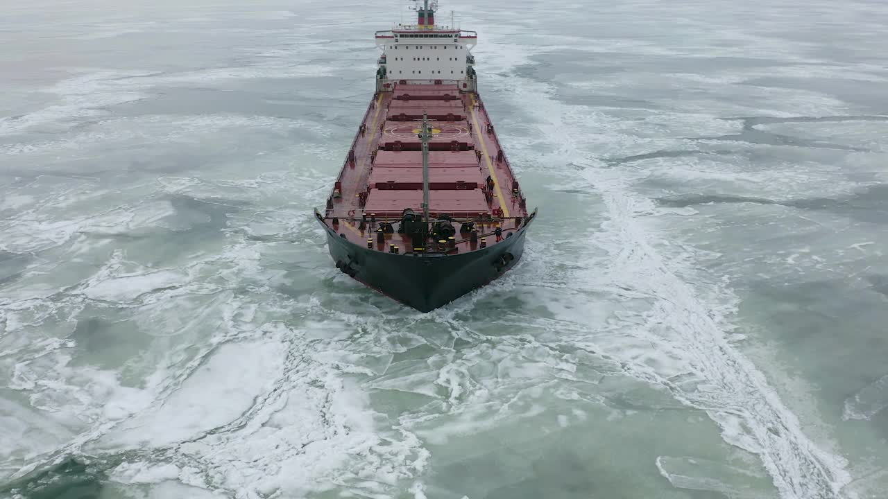 空中史诗般巨大的钢铁破冰船靠船首破冰，漂浮在巨大的浮冰上。在冰冻的航道上维持航行。自行式专用船红色船视频素材