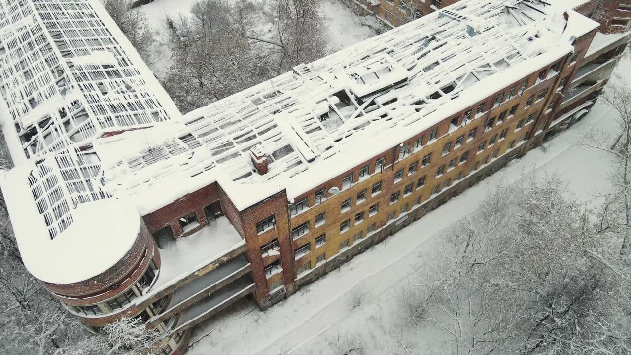 一座被雪覆盖的高层城市建筑的被毁屋顶。视频素材