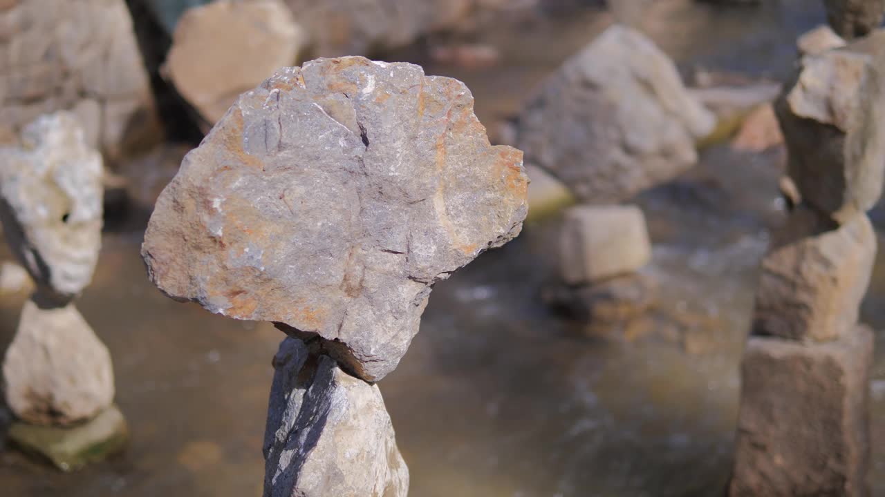 一个巨大的石头平衡在石塔上建在山上的河流。平衡的概念视频素材