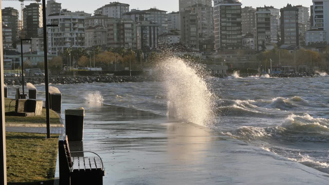 海浪拍打着海岸。公园长椅和垃圾桶都在画框里视频素材