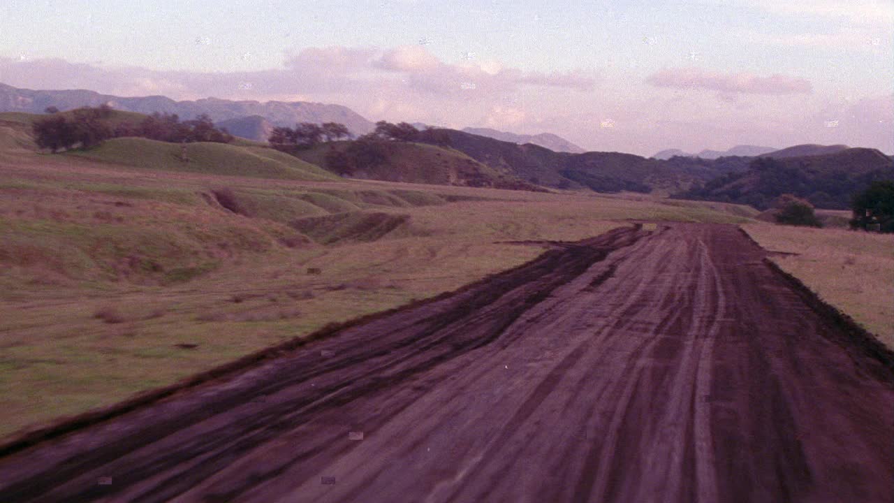 飞机从泥土跑道上起飞的空中飞行景象。飞机不可见。山脉。山。云。视频素材