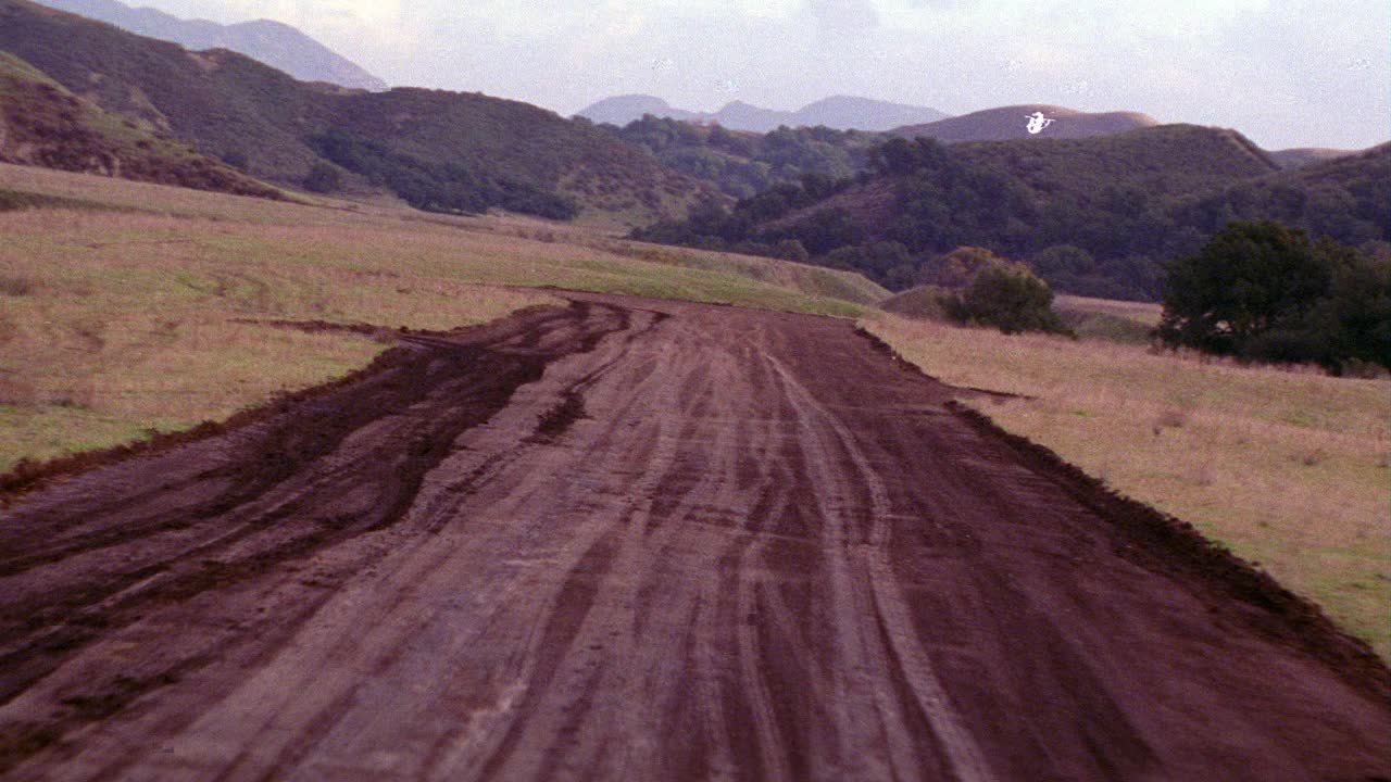 飞机从泥土跑道上起飞的空中飞行景象。飞机不可见。山脉。山。云。视频素材