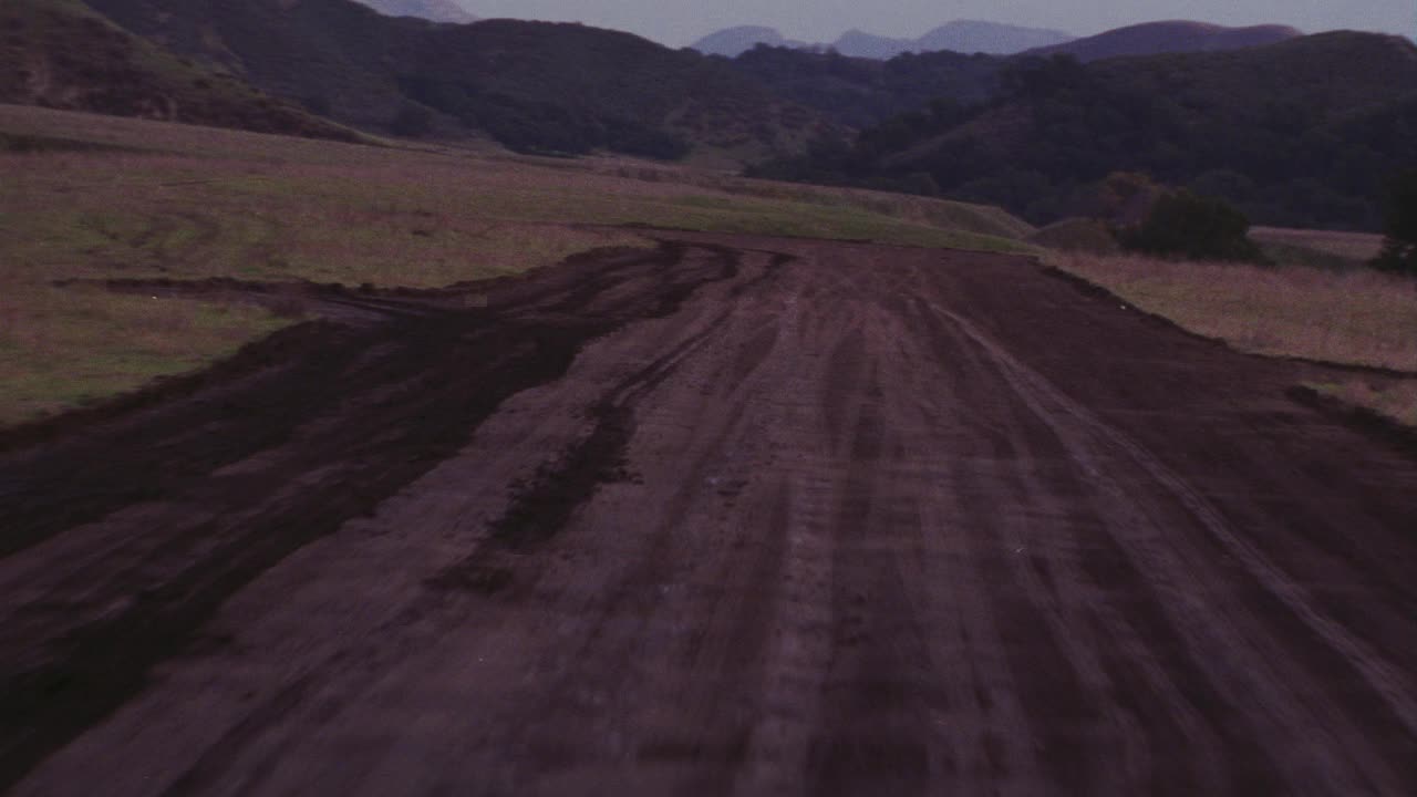 飞机从泥土跑道上起飞的空中飞行景象。飞机不可见。山脉。山。云。视频素材