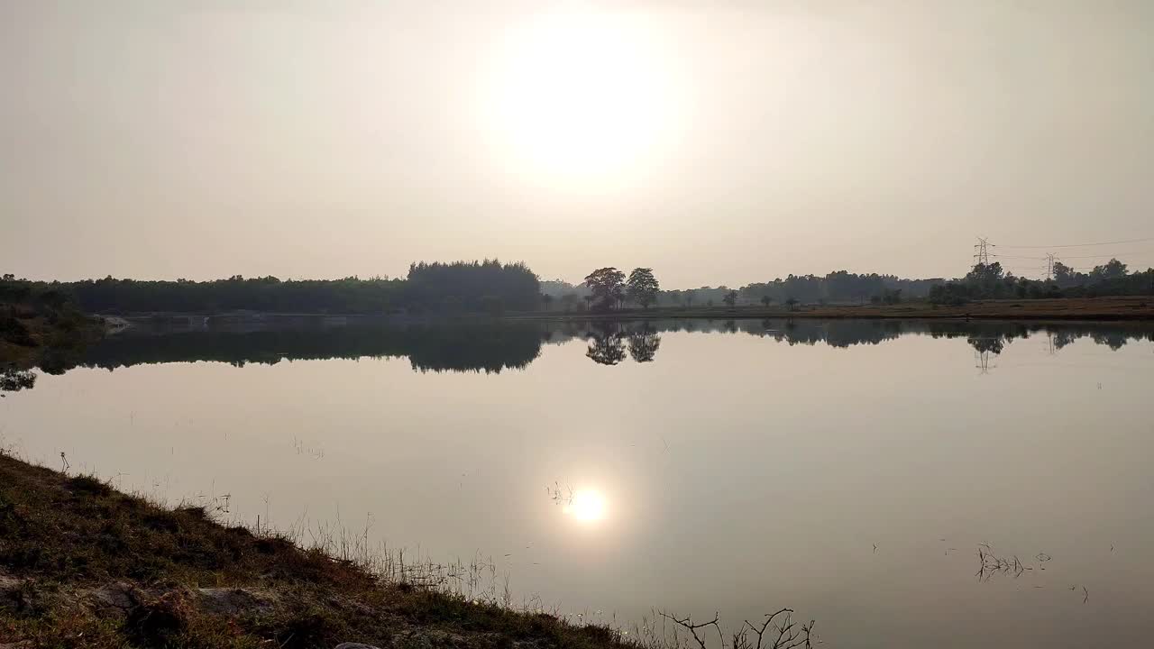 美丽的日落在印度农村地区的湖面上的时间延时拍摄。视频下载