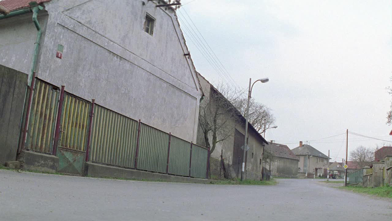 广角的庞蒂亚克gto经典汽车超速行驶在欧洲乡村的乡村道路上。道路两旁是古老的砖石建筑。村民们站在路边。视频素材