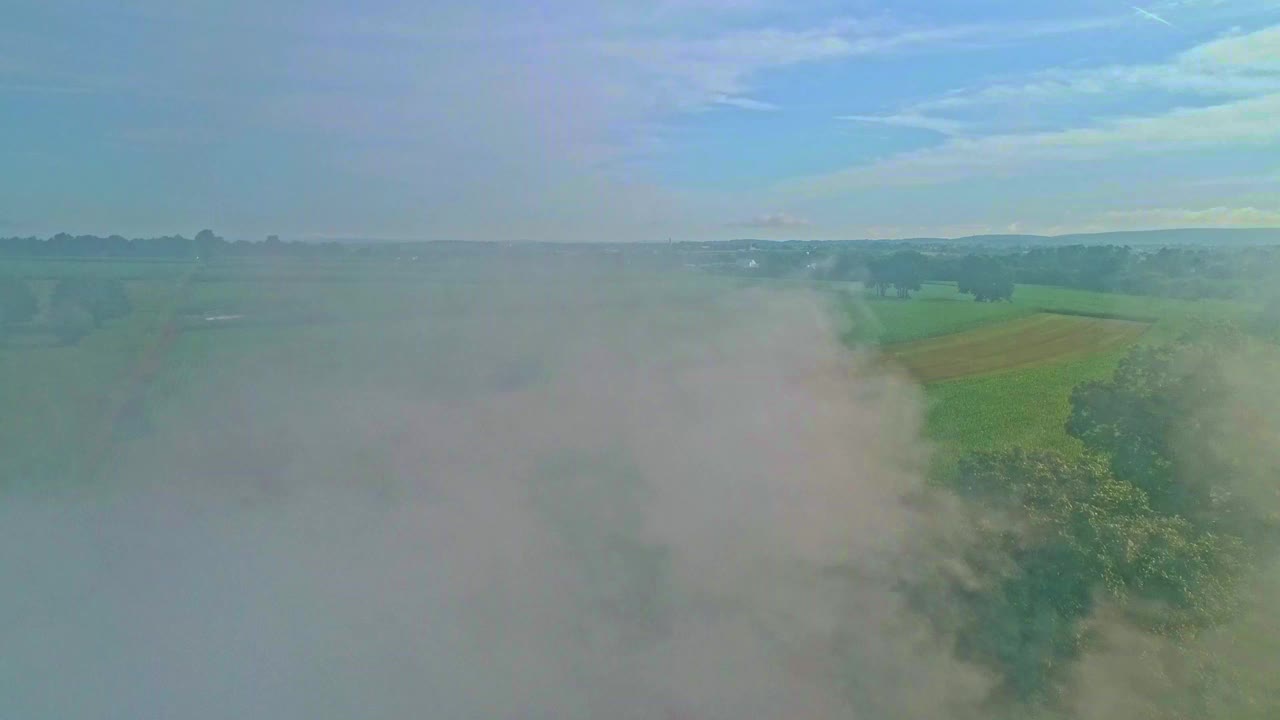 在一个阳光明媚的夏日早晨，通过烟雾看到阿米什农场的无人机视图视频素材