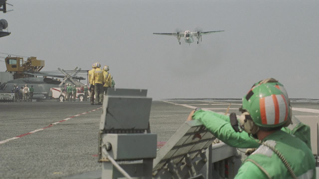 c-2a灰狗飞机中角降落在美国哈里s杜鲁门号航空母舰甲板上。飞行甲板上的机组人员正在甲板上等待飞机。螺旋桨。视频素材