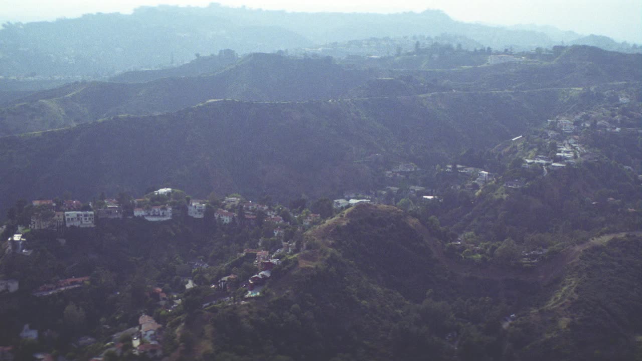 空中飞掠好莱坞山。看到上层阶级的房子和楼房在山脊和山顶之前，向下平移到好莱坞碗户外音乐厅场地。视频素材