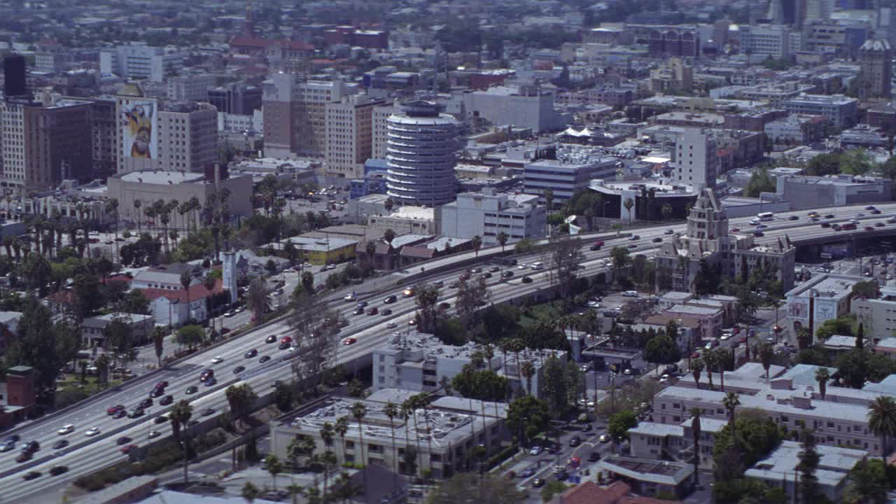 空中的好莱坞。在城市101高速公路上行驶的汽车，国会大厦记录大楼，多层办公大楼，棕榈树和树木。城市天际线或市中心的背景。地标性建筑。视频素材