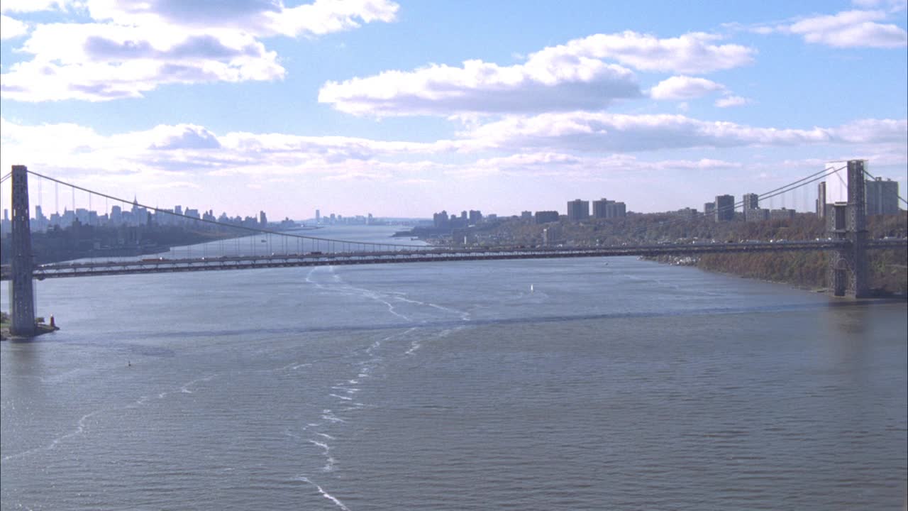 空中飞行pov在乔治华盛顿桥的顶层甲板。哈德逊河和纽约市天际线的景观。放大被堵在路上的汽车和卡车。视频素材