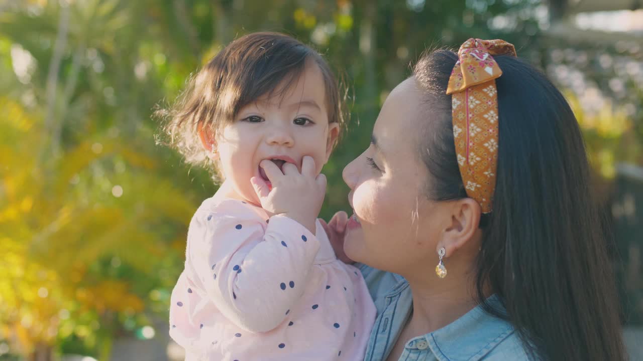 亚洲母亲亲吻她的多民族蹒跚学步的女儿的肖像，家庭爱的概念视频素材