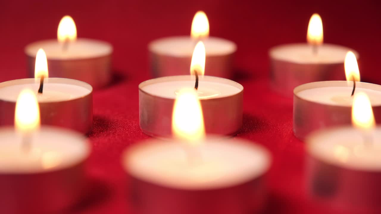 红色背景上的圣诞庆祝蜡烛。烛光为装饰，浪漫情人节视频素材