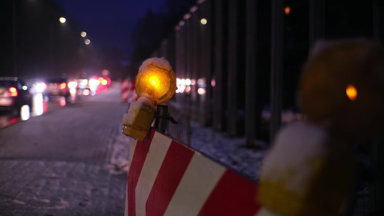 维修道路工程屏障橙色警示灯在冬季夜晚繁忙的结冰道路及交通挤塞情况下依次闪烁视频素材