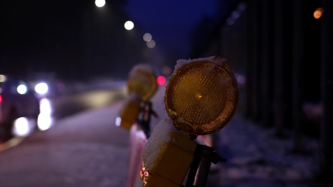 维修道路工程屏障橙色警示灯在冬季夜晚繁忙的结冰道路及交通挤塞情况下依次闪烁视频素材