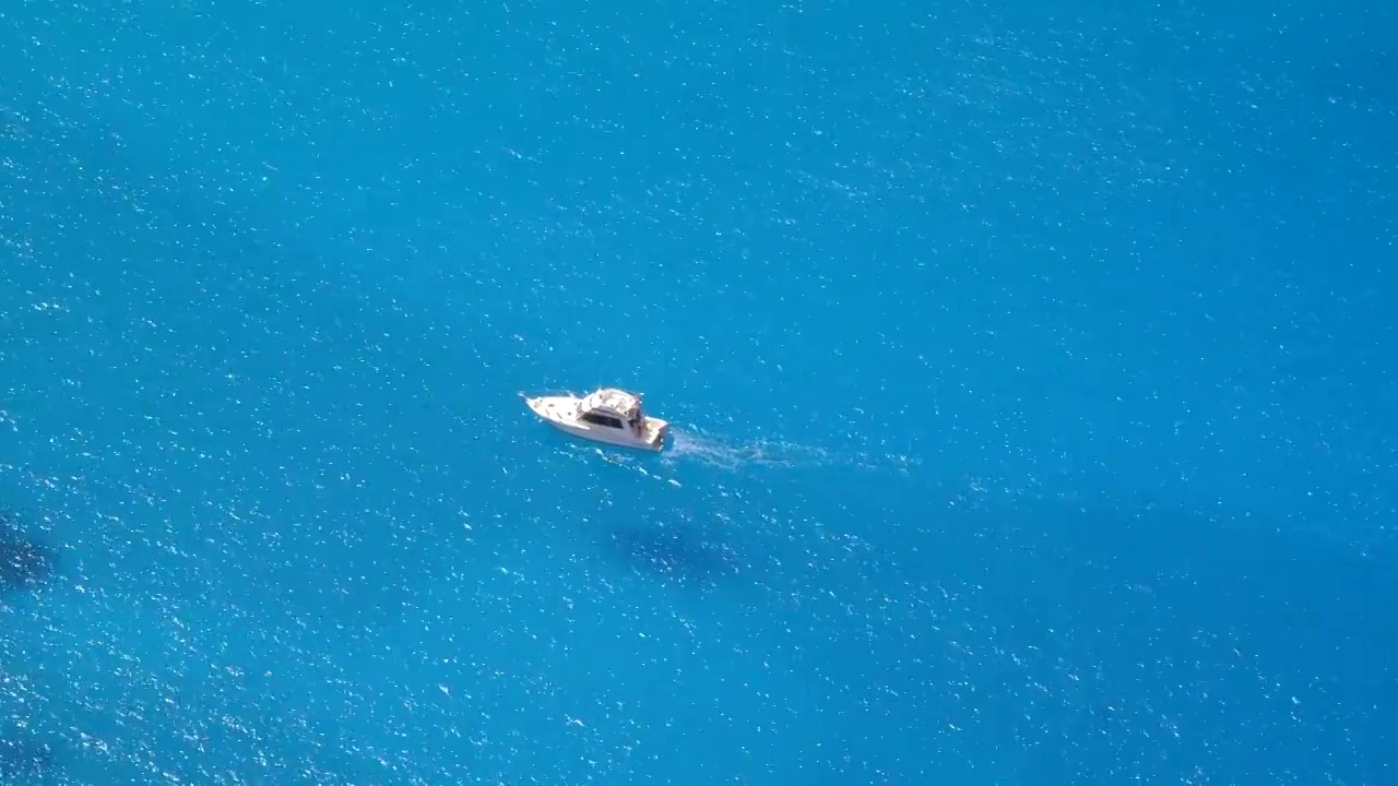 小船漂浮在清澈平静的蓝色水域视频素材