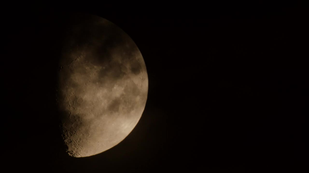 不完整的月亮在夜空中移动，伴随着小云朵。视频素材