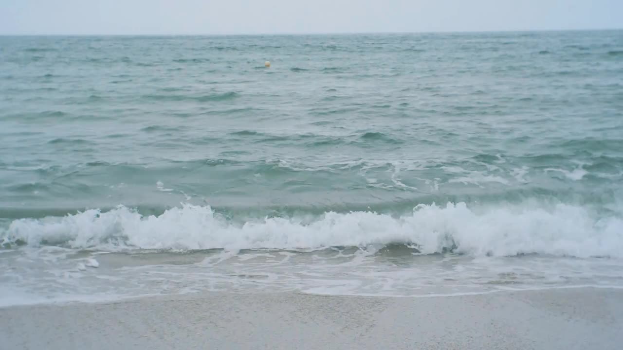 在多云的日子里，海浪拍打着沙滩视频素材