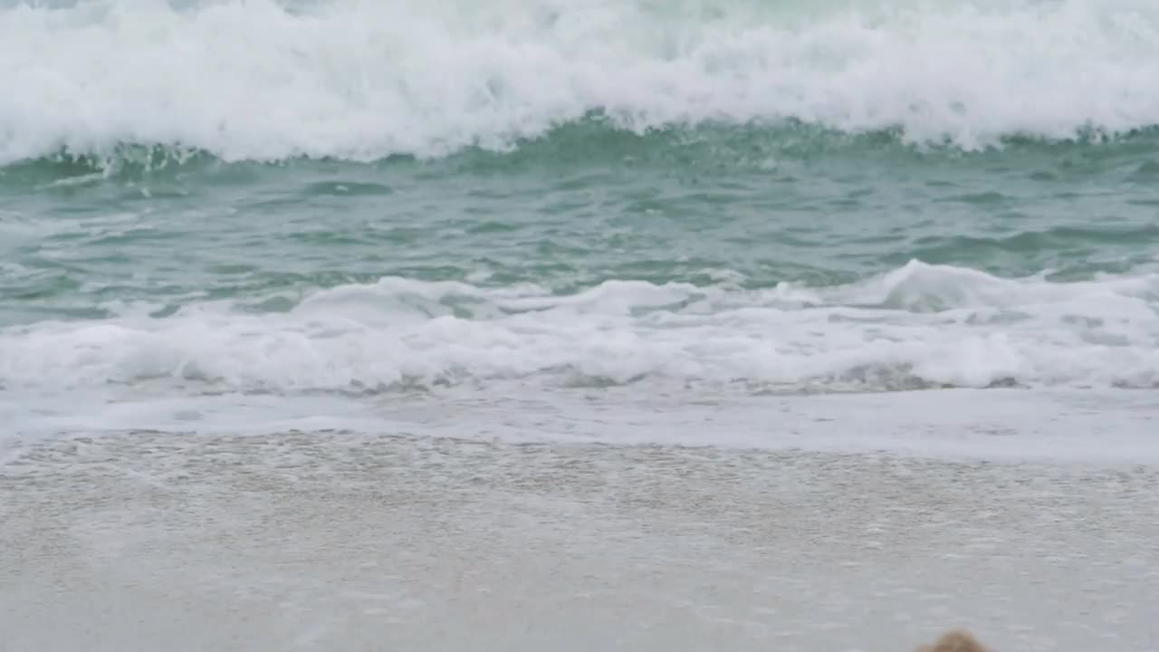 在多云的日子里，海浪拍打着沙滩视频素材