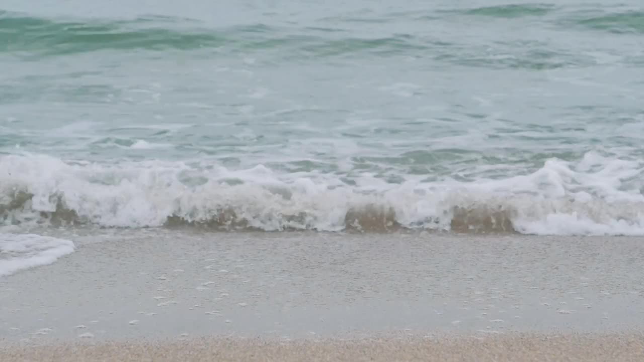 在日出期间，年轻女子沿着海滩行走的双腿。女孩踩在潮湿的沙滩上。视频素材