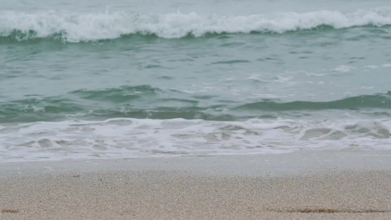 在日出期间，年轻女子沿着海滩行走的双腿。女孩踩在潮湿的沙滩上。视频素材