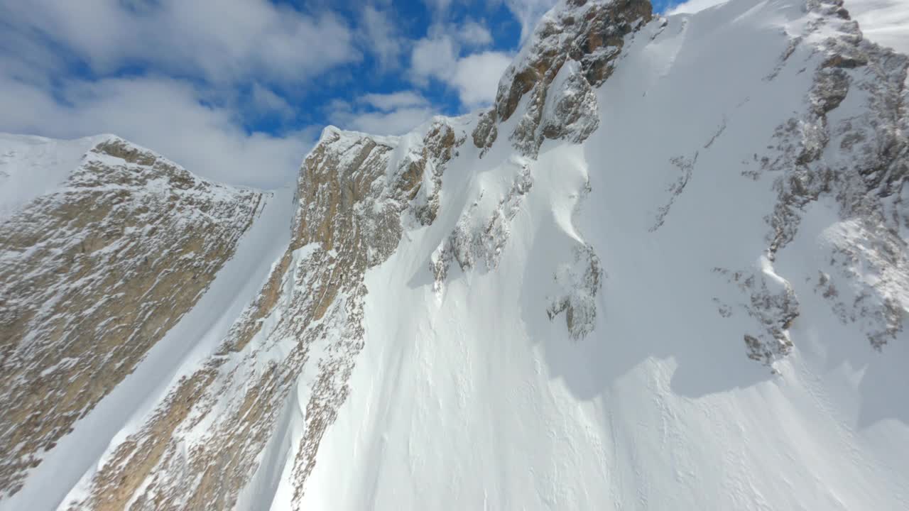 鸟瞰运动FPV无人机攀登上升到自然山顶史诗般的冬季雪景视频素材