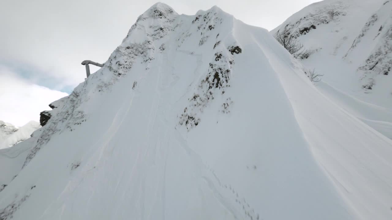 鸟瞰图运动FPV无人机飞上山山脊与人从顶部骑上滑雪板视频素材