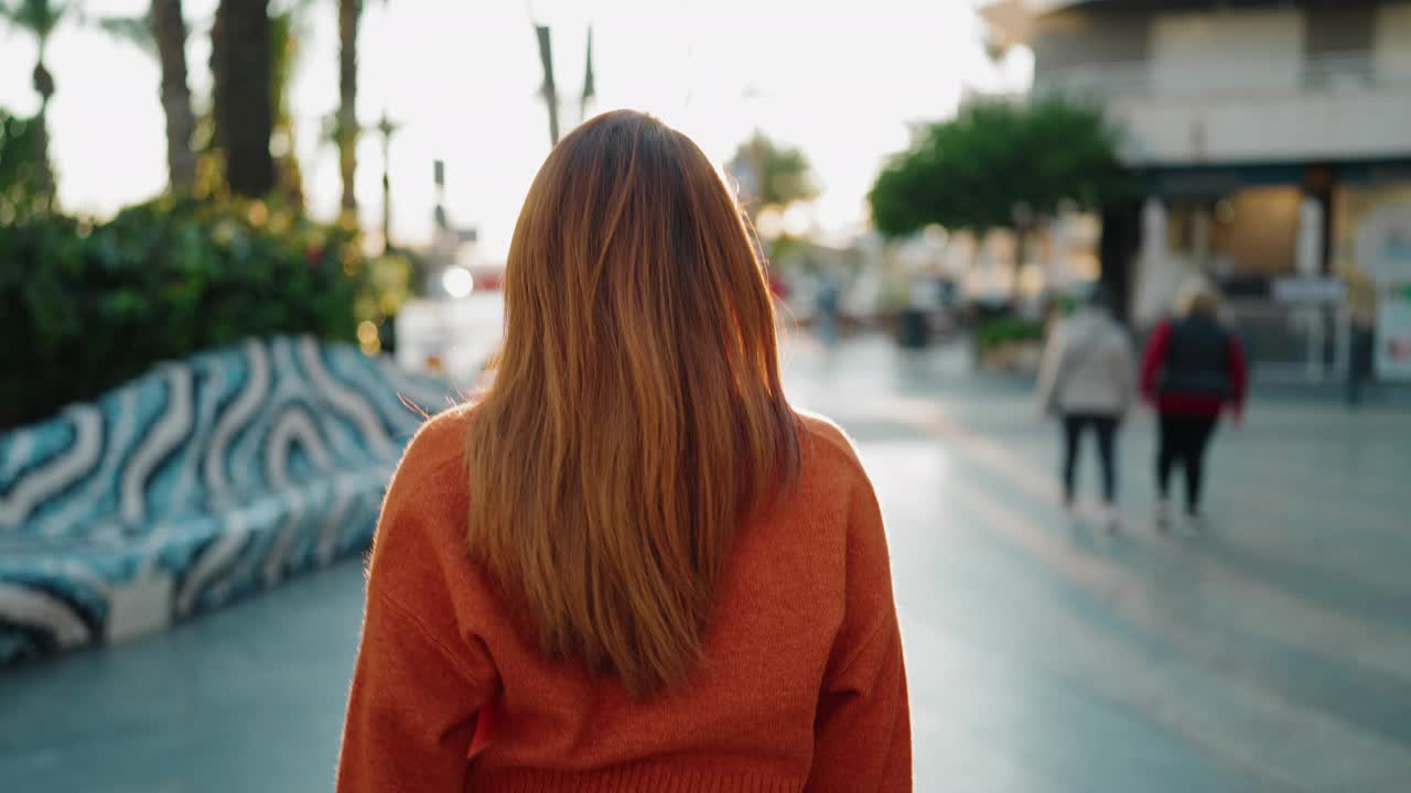 年轻的红发女子微笑自信地走在街上视频素材