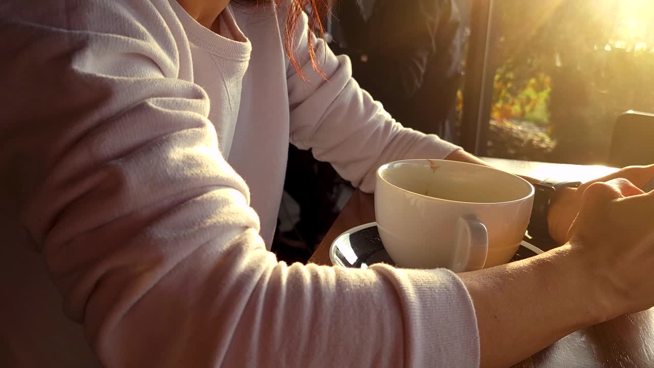 视频中，一名年轻女子一边用手机一边看屏幕上的电子邮件或信息视频素材