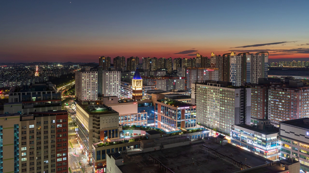 韩国京畿道始兴市百歌新城市附近的威尼斯广场购物中心的钟楼和写字楼公寓的夜景视频素材