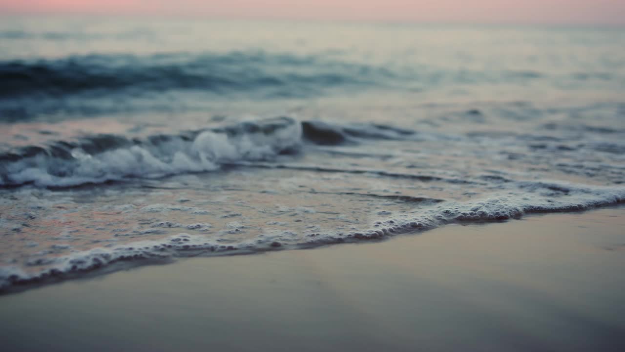 寒冷的早晨，海浪拍打着海岸线上的沙滩。水面视频素材