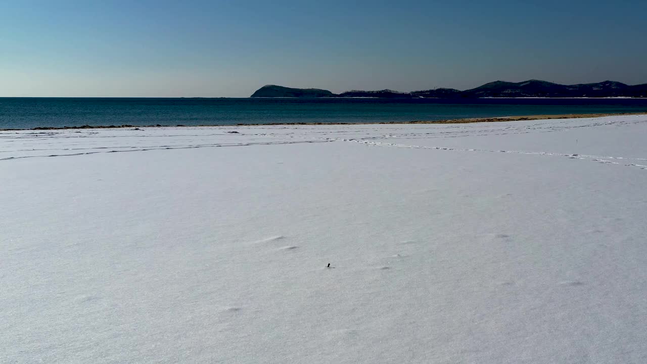 这是覆盖着白雪的海滩的海岸线的鸟瞰图。视频素材