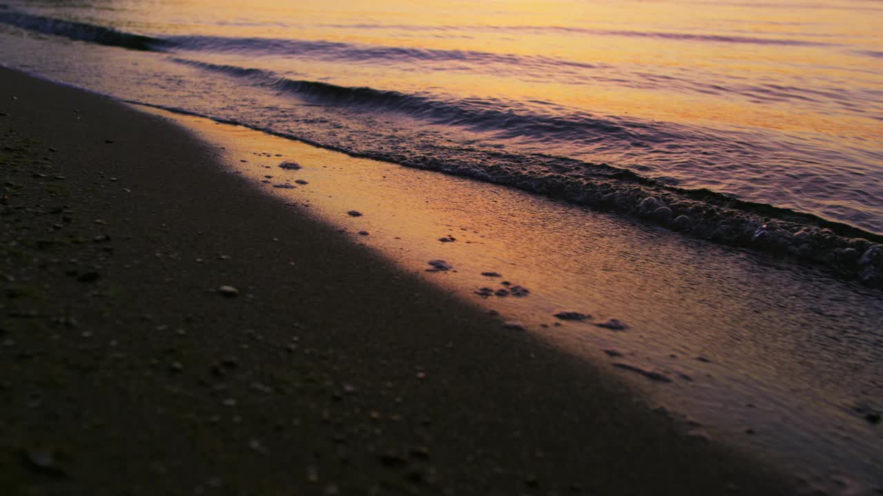 特写海浪拍打沙滩在寒冷的傍晚日落黄昏慢动作视频素材