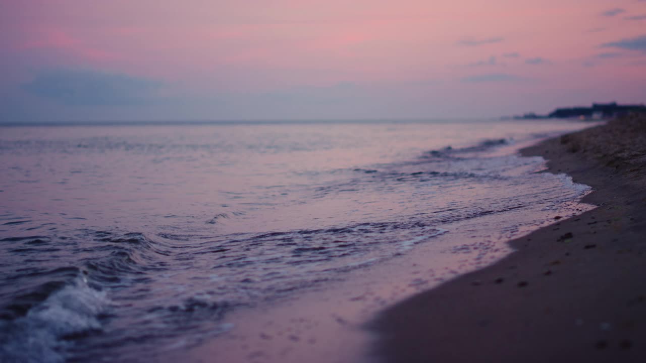 紫色的天空反射在海面在寒冷的傍晚日落。平静的海浪视频素材