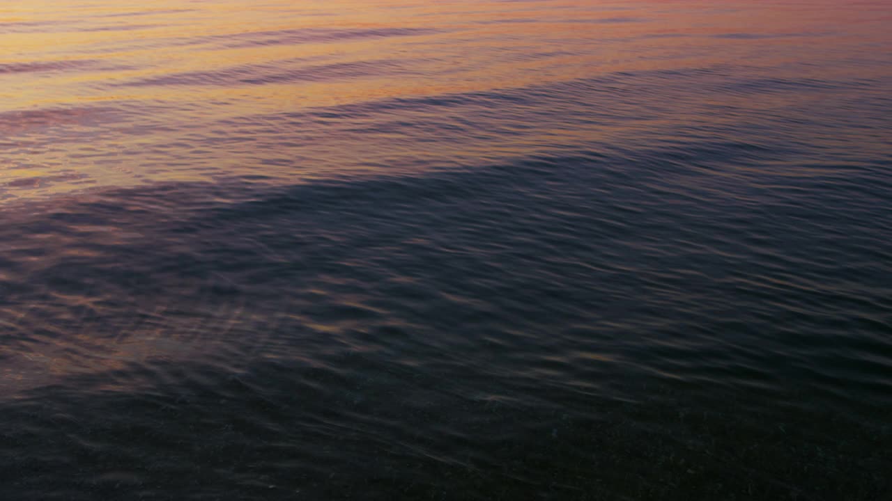 特写平静的海水表面反射明亮的粉红色日出天空在早晨视频素材