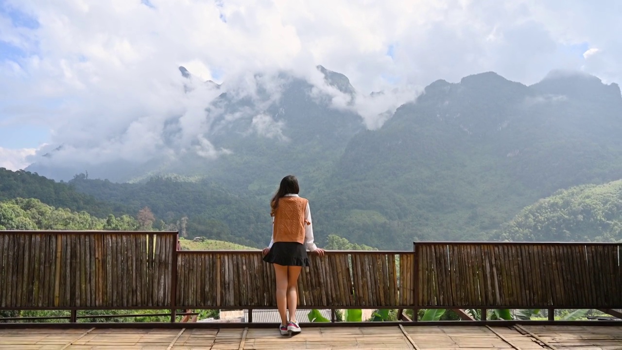 亚洲妇女在阳台上散步，欣赏山景视频素材