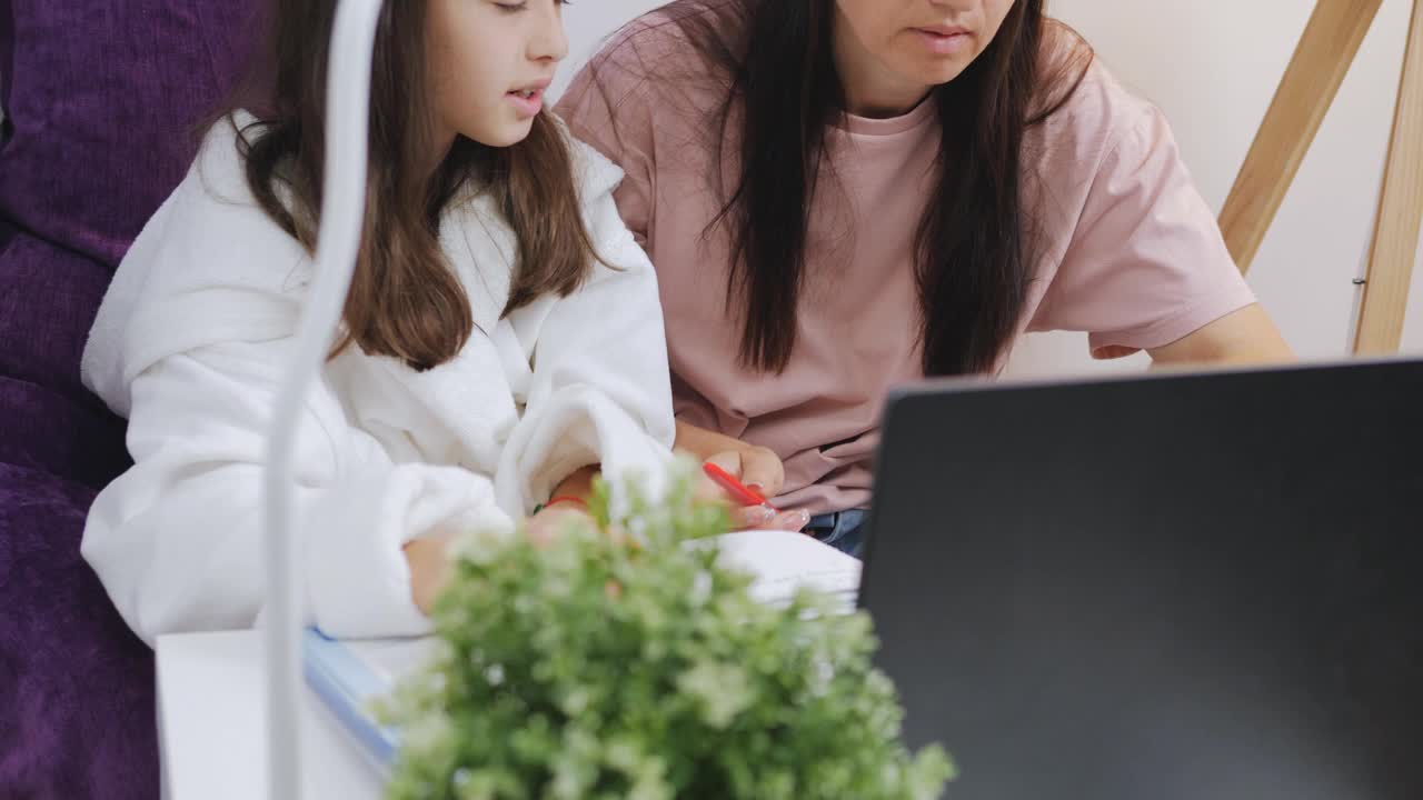 一位妇女和她的女儿一起在笔记本电脑前做作业或远程学习。视频下载