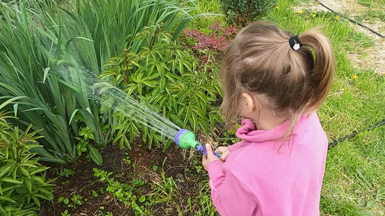 小女孩用软管喷壶给花园浇水视频素材