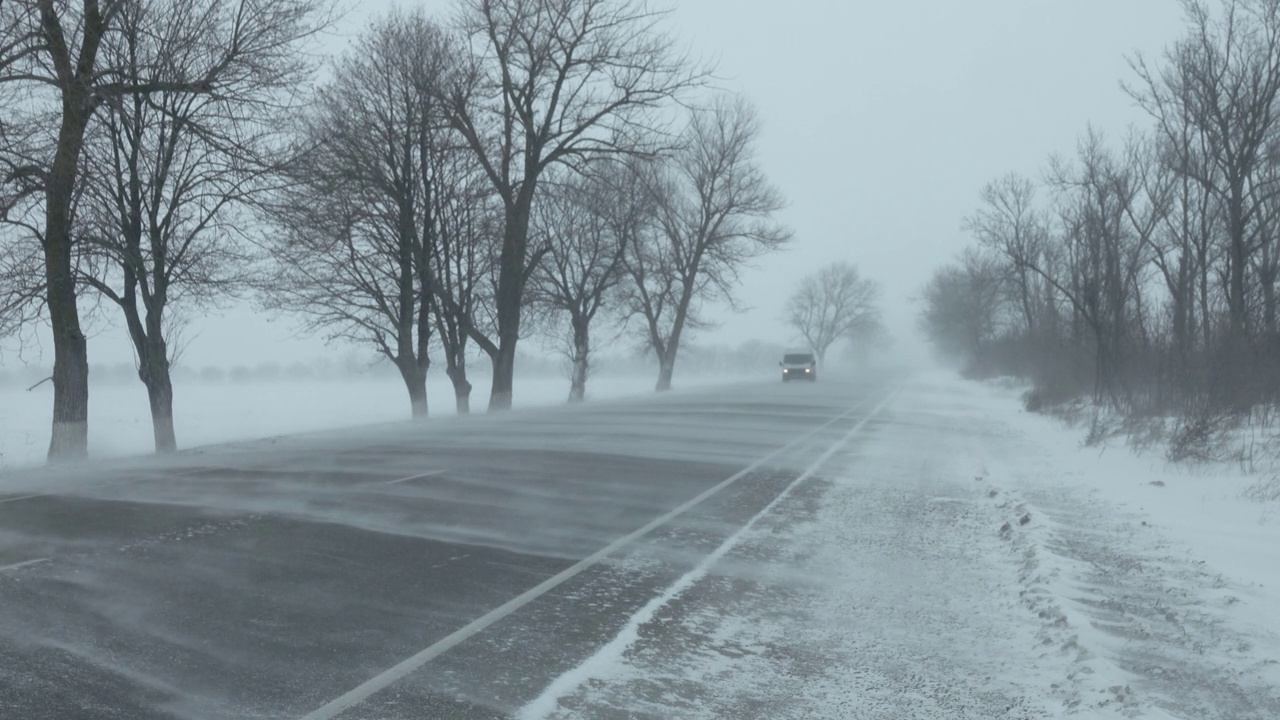 暴风雪中行驶在冬季道路上的汽车视频素材