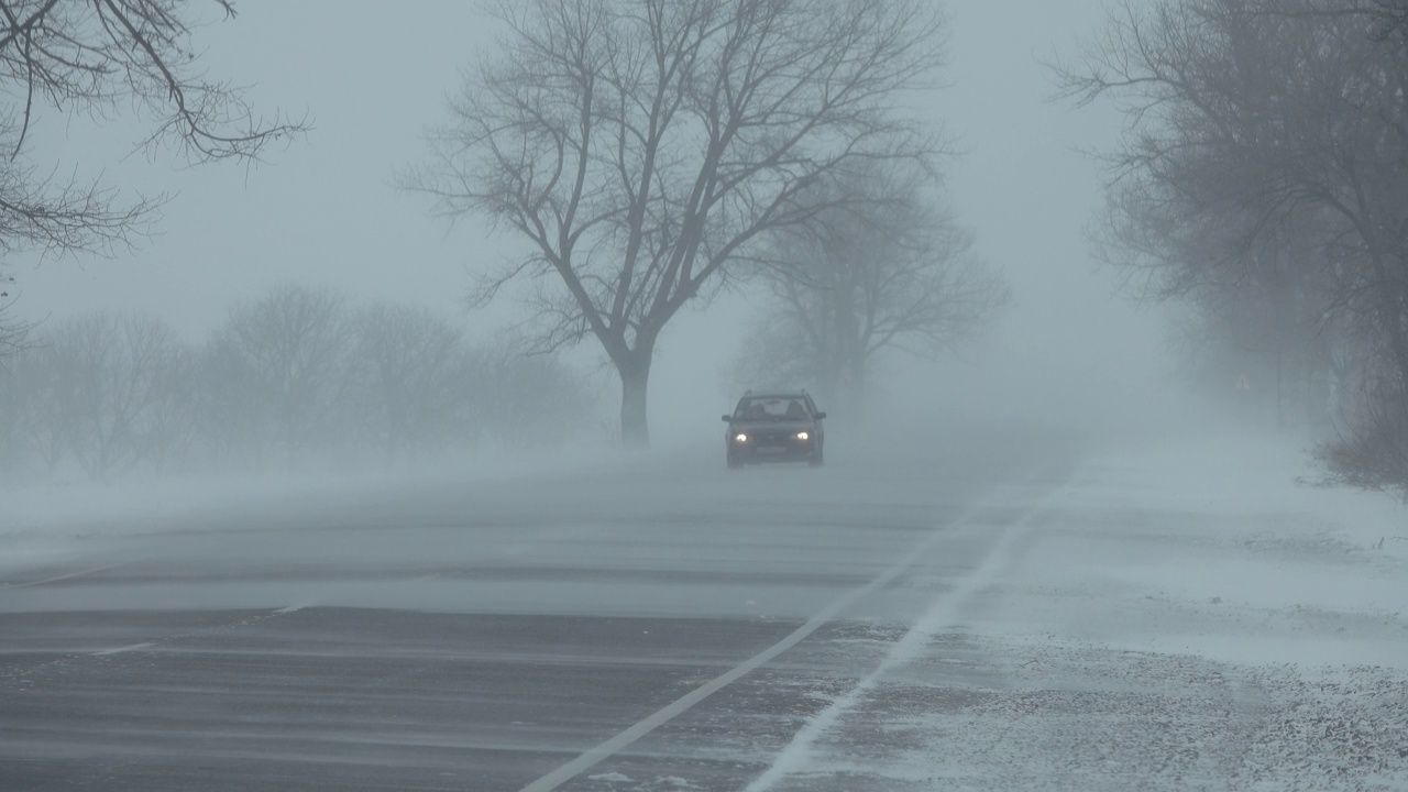 暴风雪中行驶在冬季道路上的汽车视频素材