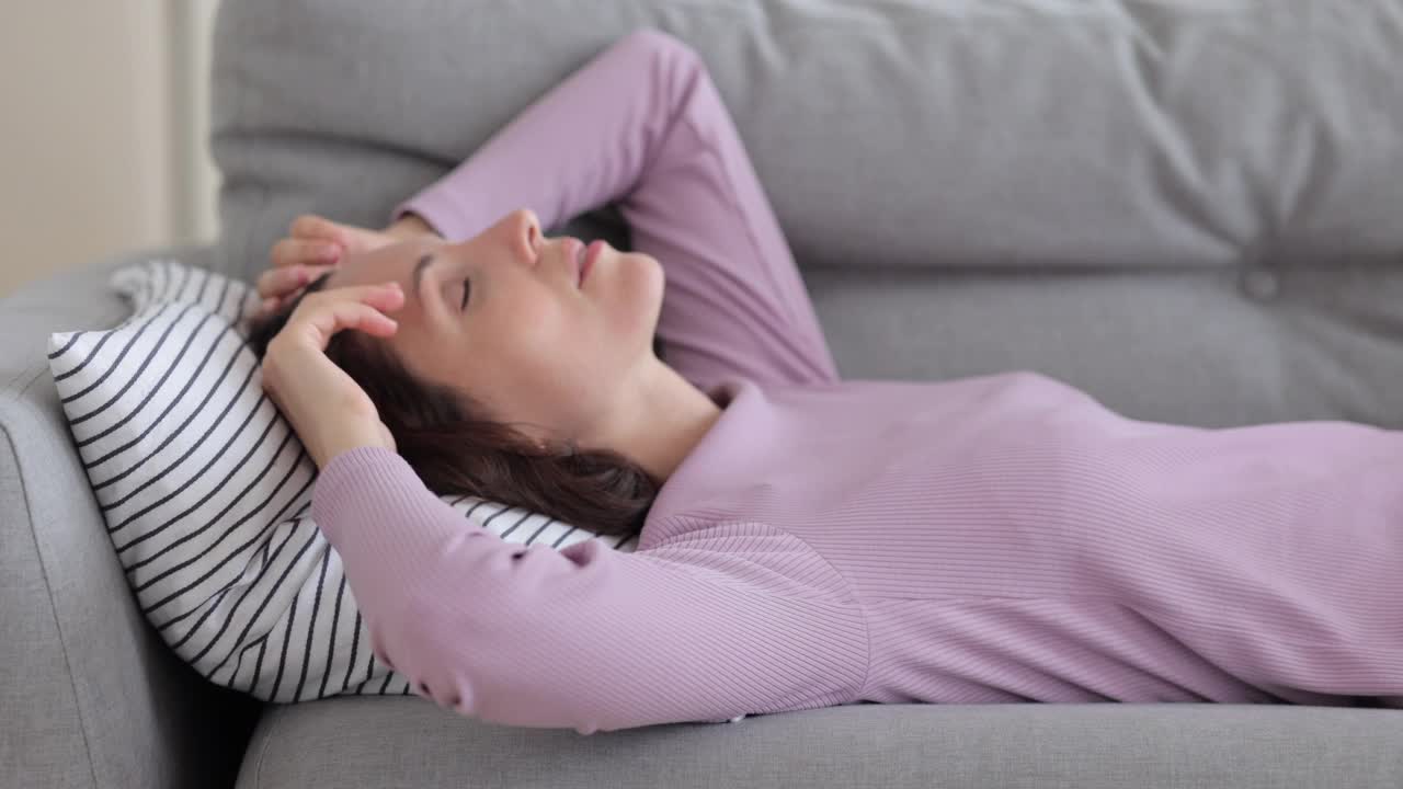 女人躺在沙发上遭受痛苦，睡眠障碍或来自邻居的噪音试图放松填补坏视频素材