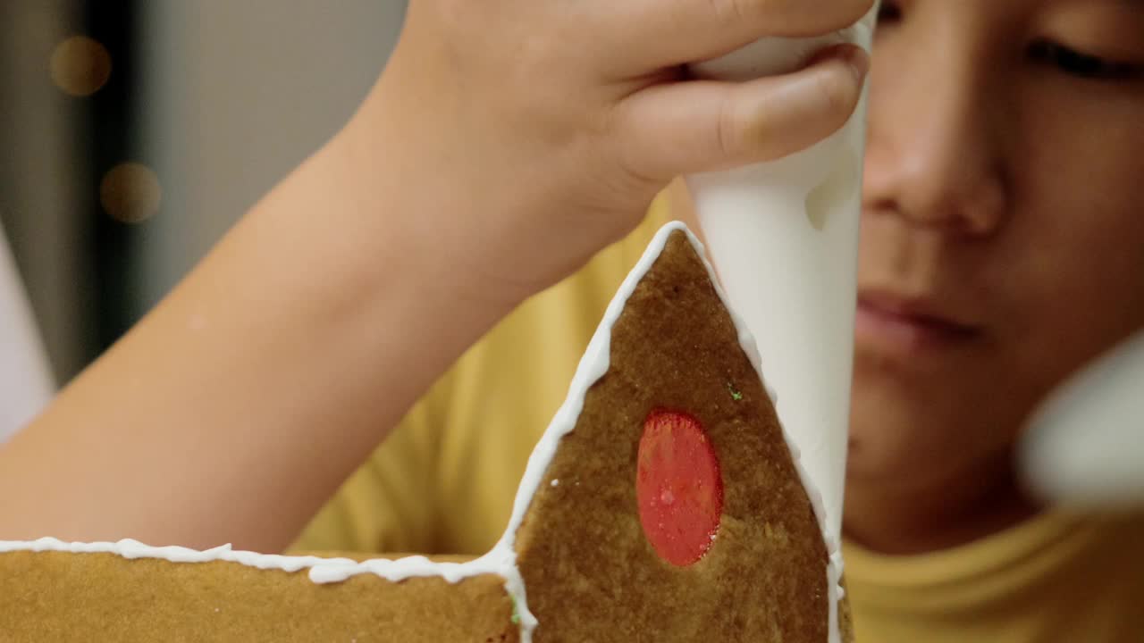 亚洲男孩和妹妹在晚上在家做姜饼屋，庆祝圣诞节的生活理念。视频素材