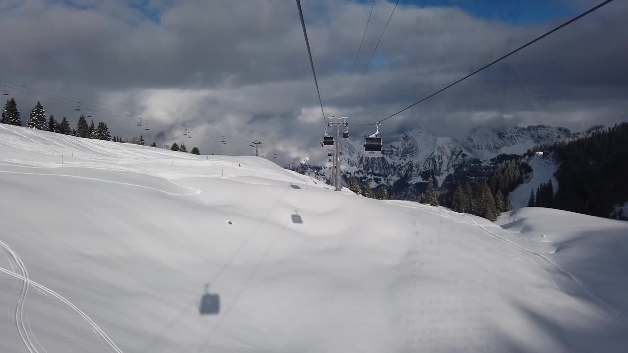 瑞士山区度假胜地Flumserber的滑雪椅升降机视图。白雪覆盖的山脉，阳光灿烂的日子，无法辨认的游客，实时的。视频素材