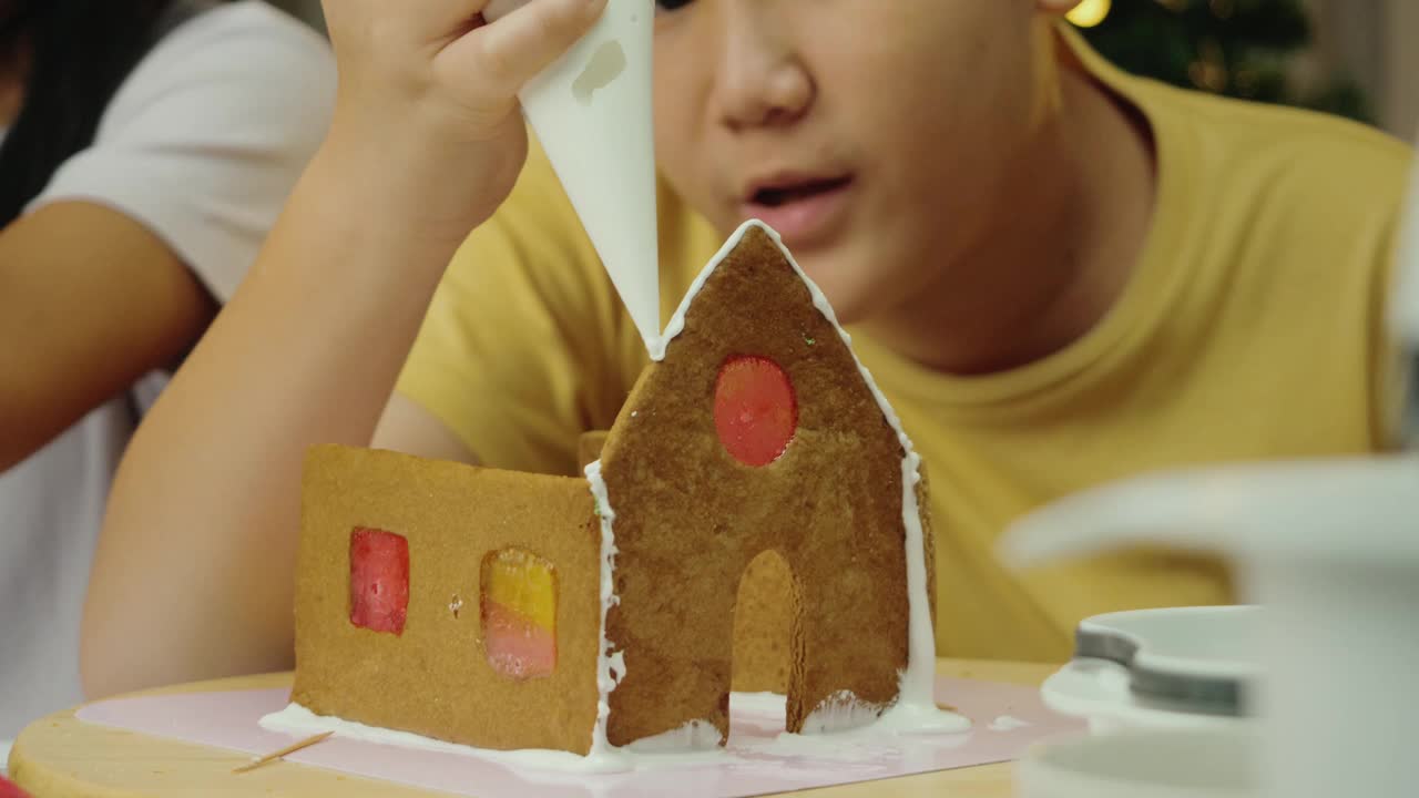 亚洲男孩和妹妹在晚上在家做姜饼屋，庆祝圣诞节的生活理念。视频素材