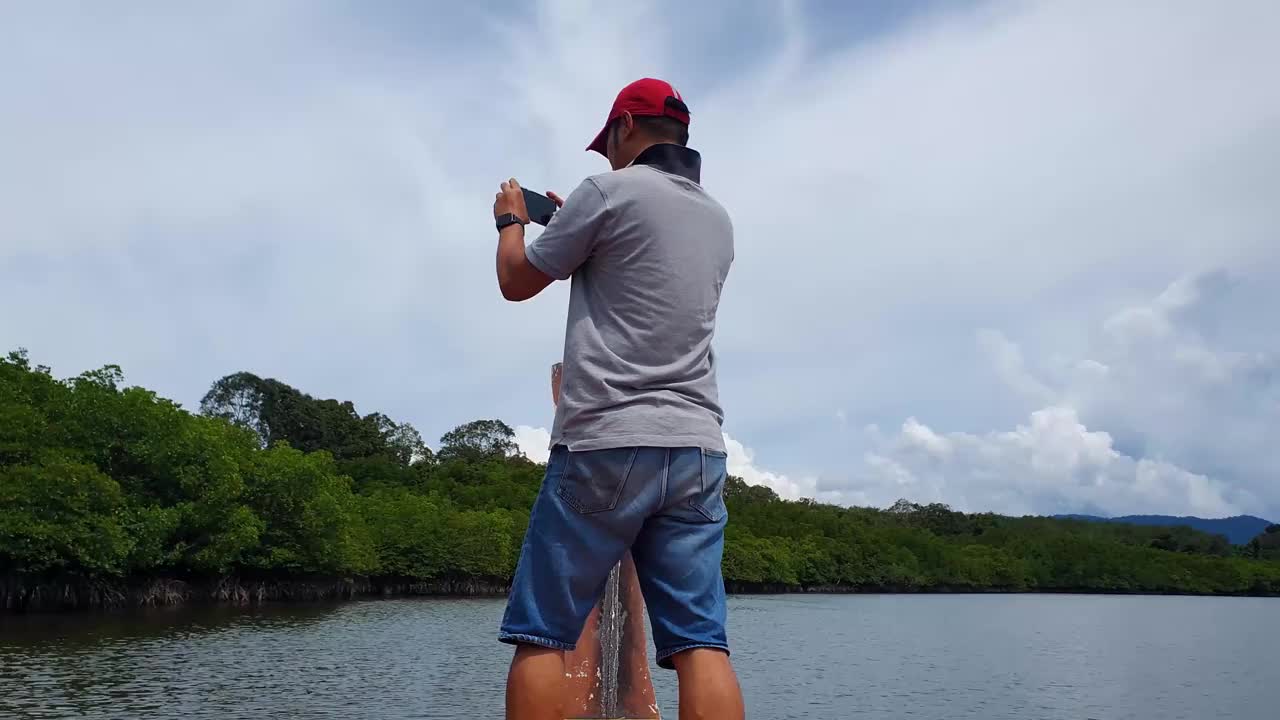 男人站在船上，河景红树林森林之旅视频素材