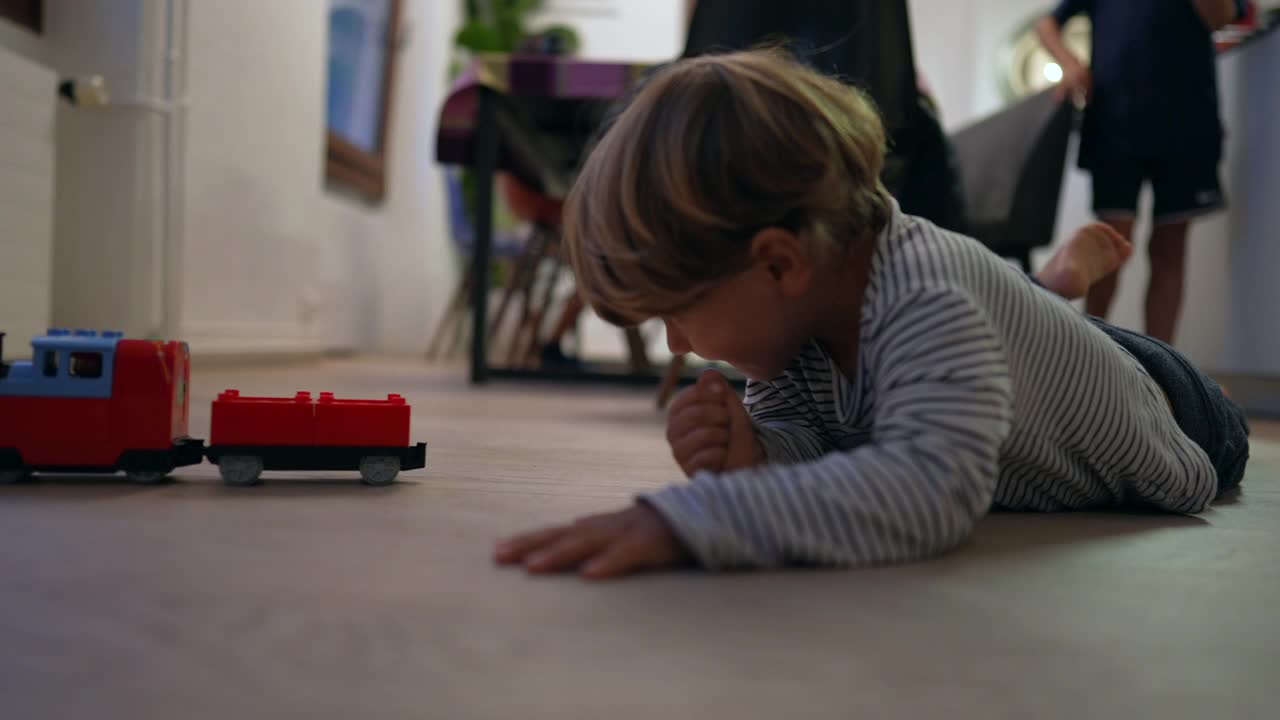 小孩在硬木地板上玩玩具。孩子在家玩视频素材