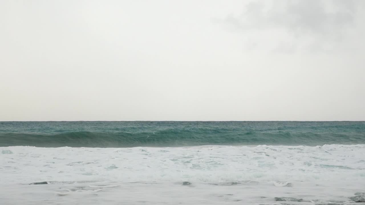 狂风暴雨，海面波涛汹涌。海浪冲击海岸线，造成海水爆炸。巨大而有力的海浪拍打着海滩，产生白色的泡沫。美丽的海上风景视频素材