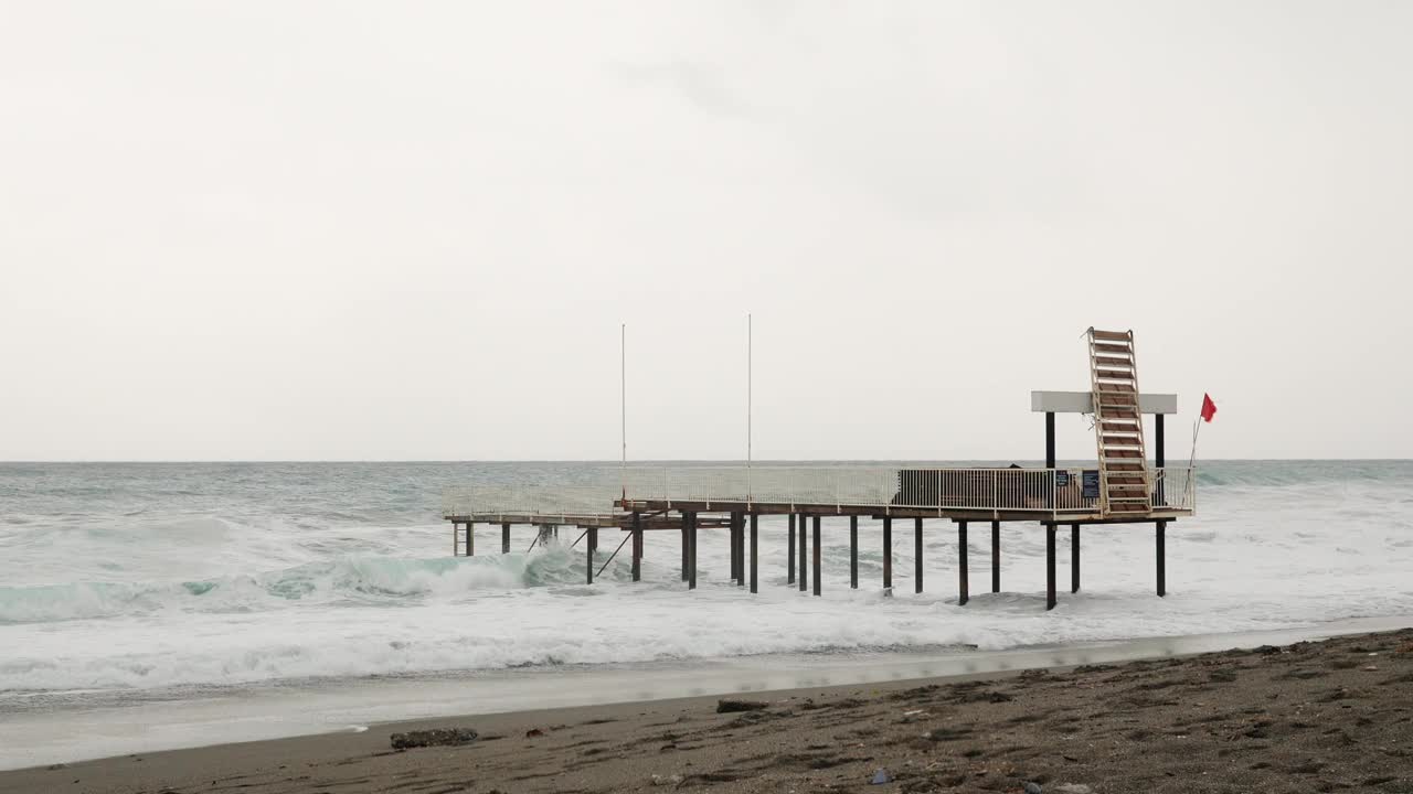 风浪汹涌的海上空码头。强大的海浪冲击着沙滩，溅起白色的泡沫。在刮风的日子里，波涛汹涌的大海视频素材