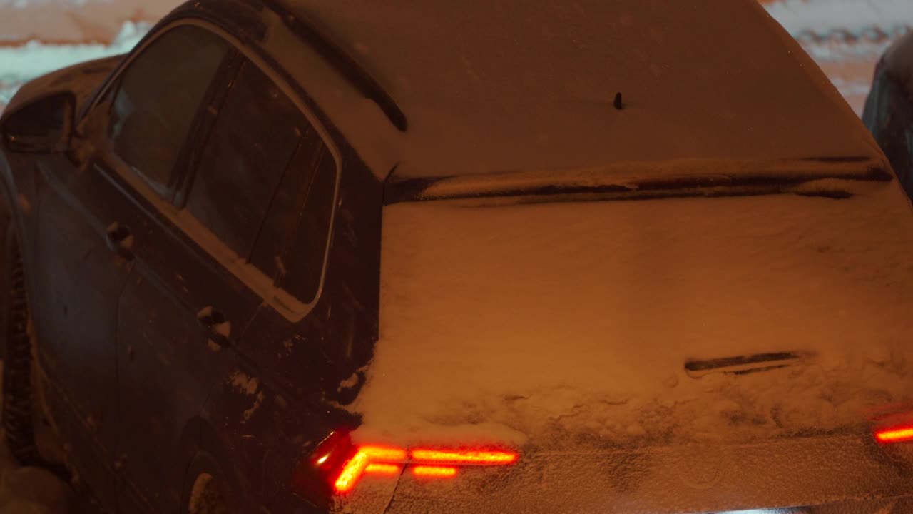 冬天，停车场的路灯下停着的汽车在黄昏时被雪覆盖。城市街道上的大雪。视频素材