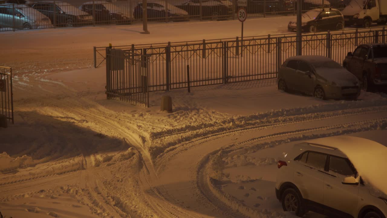 冬天黄昏时分，一幢公寓楼附近的停车场被雪覆盖。视频素材